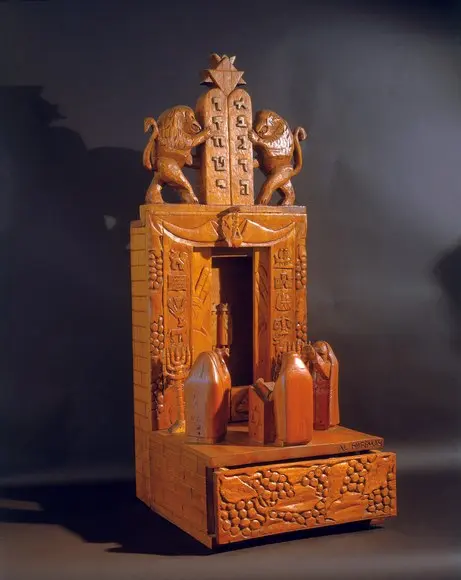 A carved wooden ark topped with lions and the tablets of the law by Albert Hoffman.