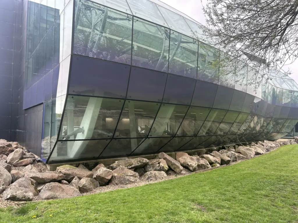 The curved glass facade of Arclite House over rocks