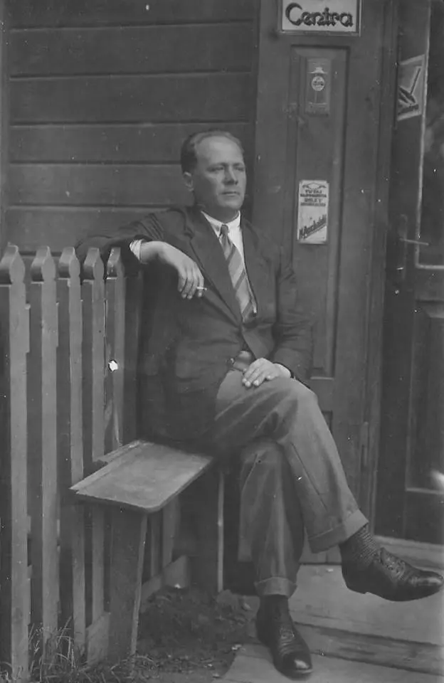Edmund Monsiel photographed seated outside a shop.