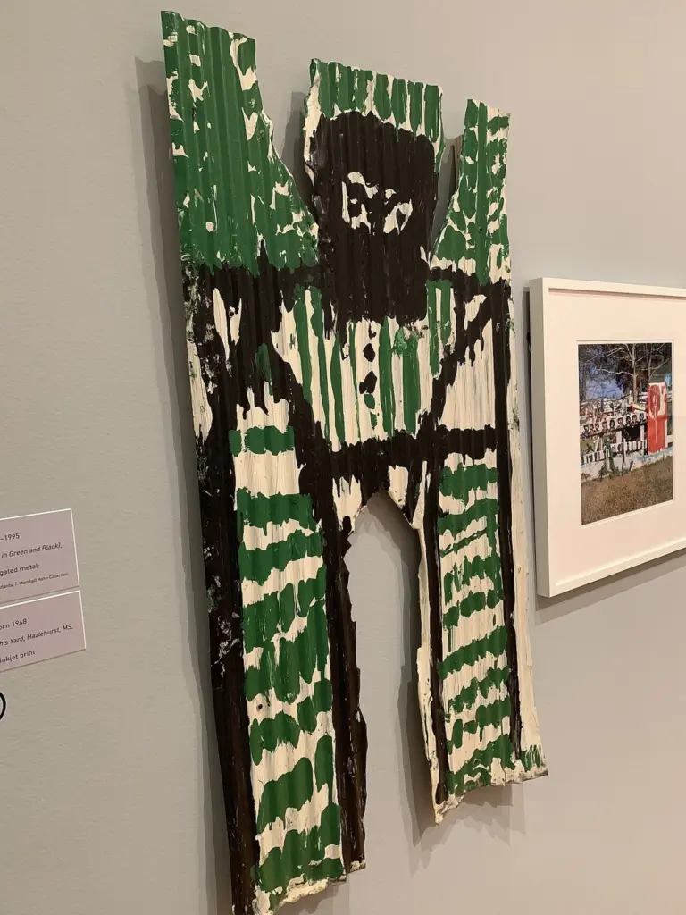 A figure painted on corrugated metal by Mary T. Smith, on display in a museum gallery.