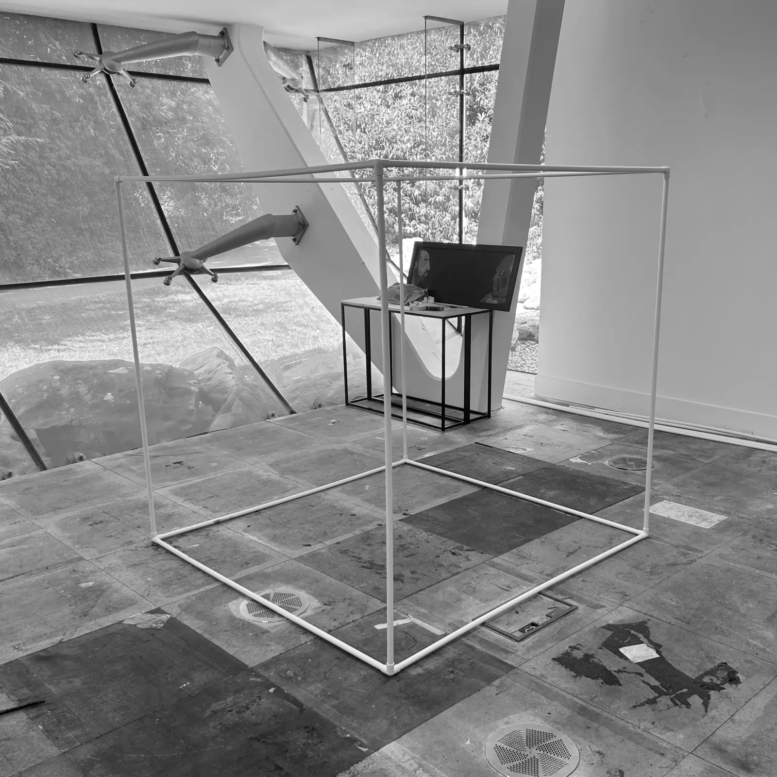 A bare white cube frame of plastic tubing standing in the studio at Arclite House