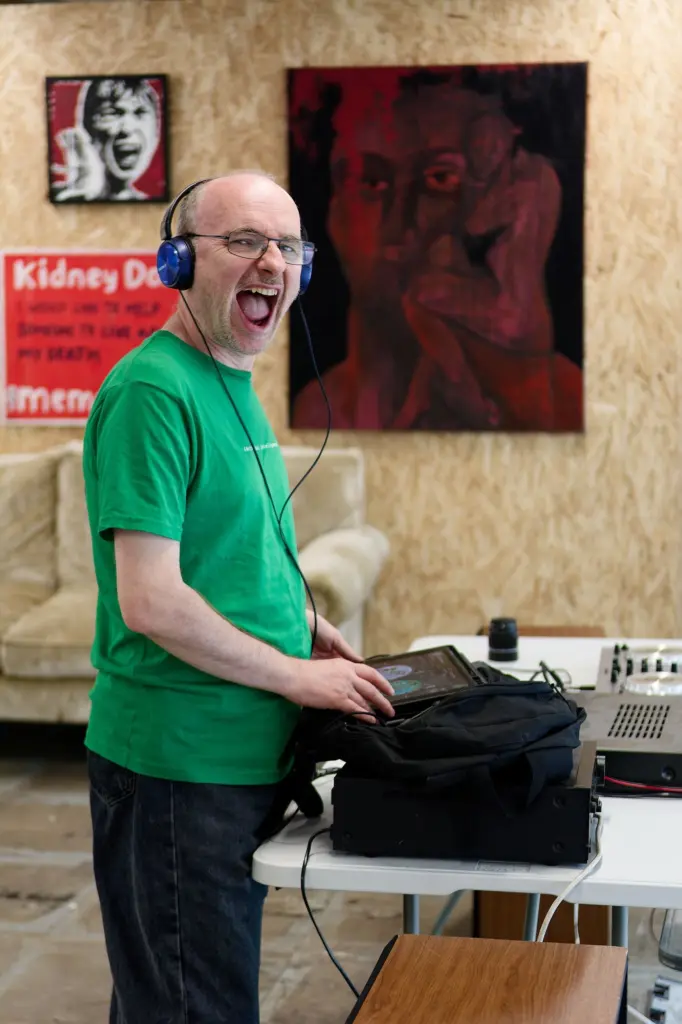 Local Swindon DJ, DJ Dust, playing music beside a red painting