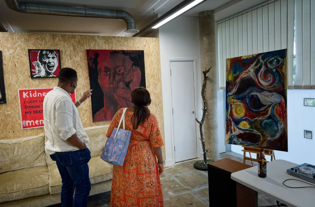 Two visitors looking at paintings on the board wall