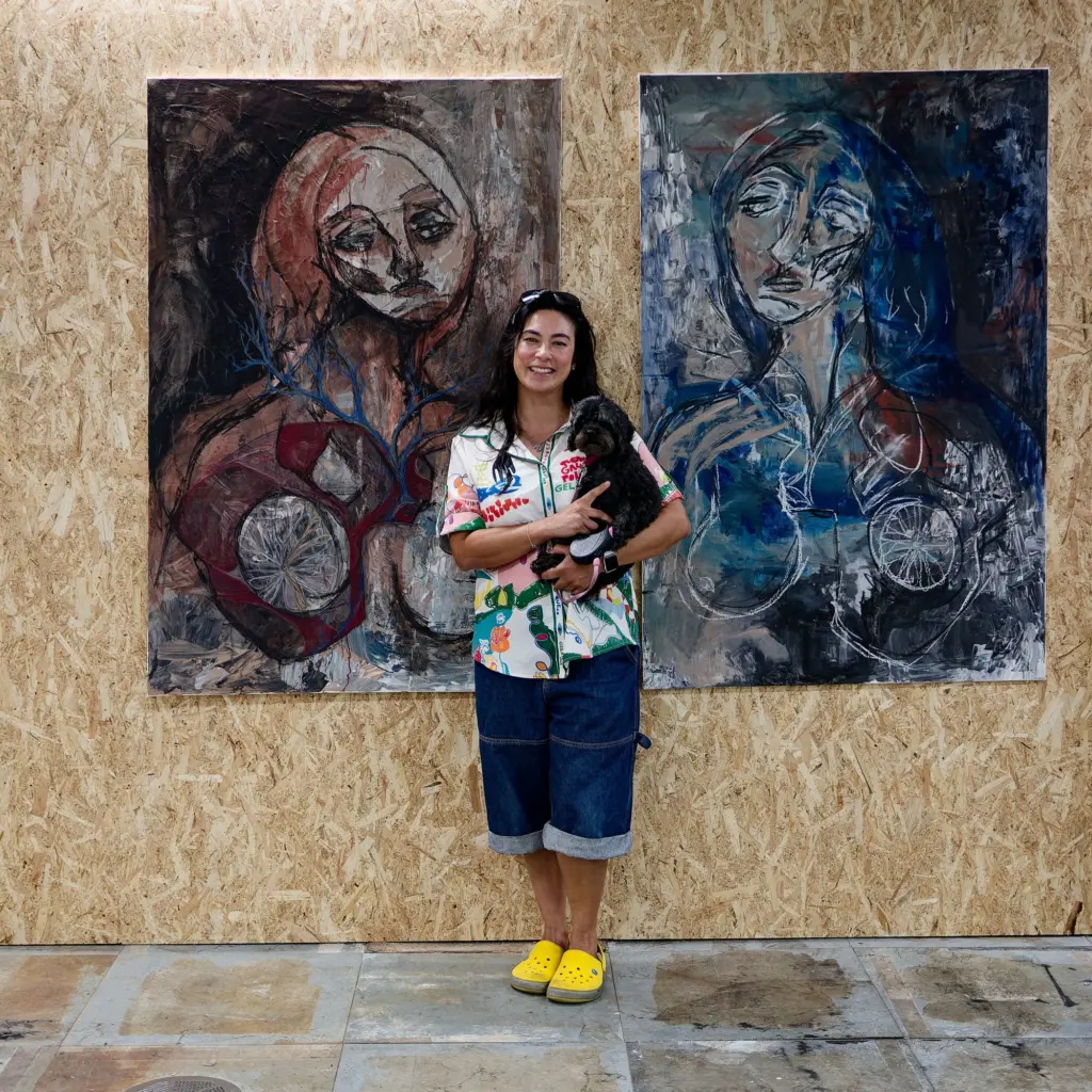 A visitor photographing a large blue and red portrait painting