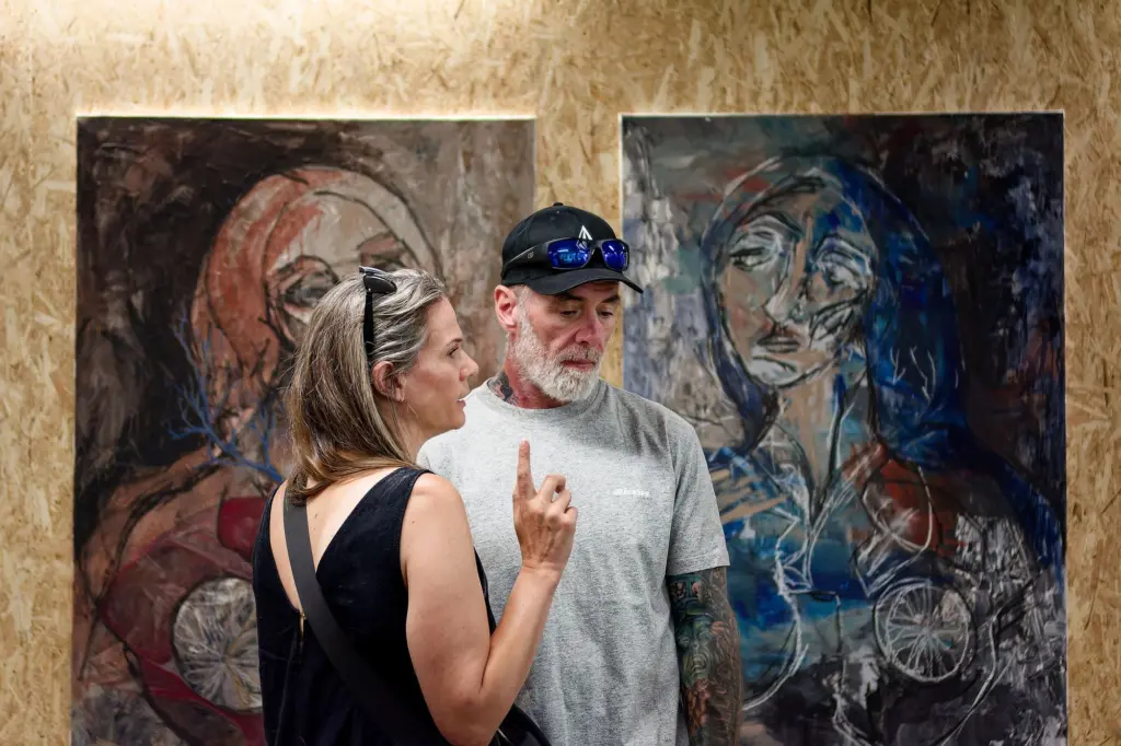 Two guests in front of a large blue and pink portrait painting
