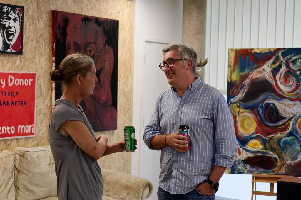 A guest holding a drink beside a bright abstract painting