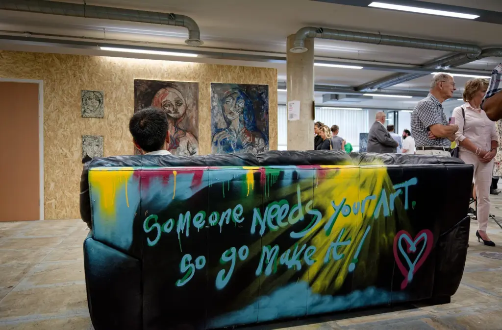 The hand-painted bar sign reading "Someone needs your art, so go make it"