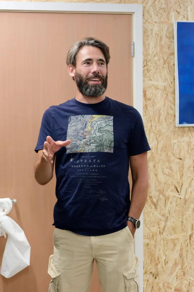 Co-founder SLART holding a glass in front of hung artwork