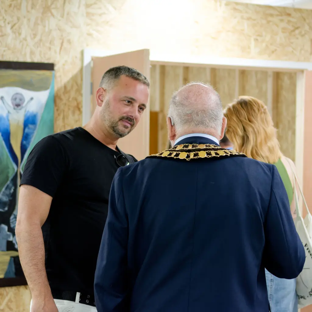 Two guests in conversation beside the studio window