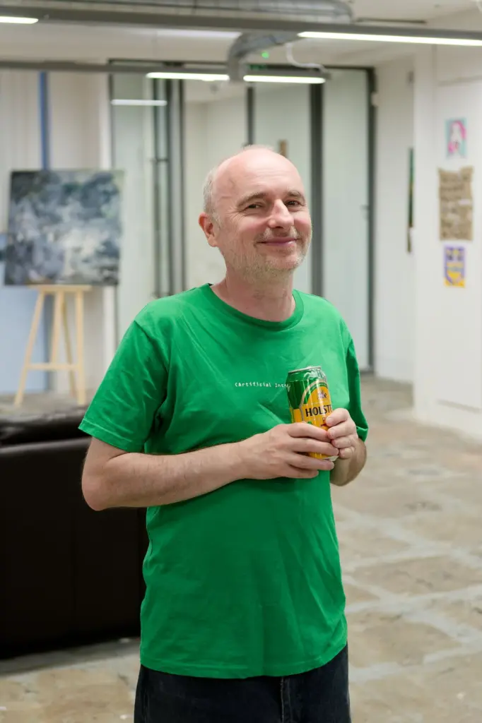 A guest in a green shirt holding a drink at the opening