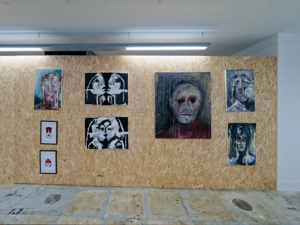 A wall of framed portrait drawings in the studio corridor