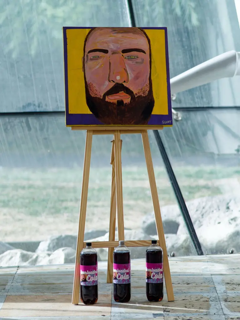 A painted portrait on an easel beside the studio glass