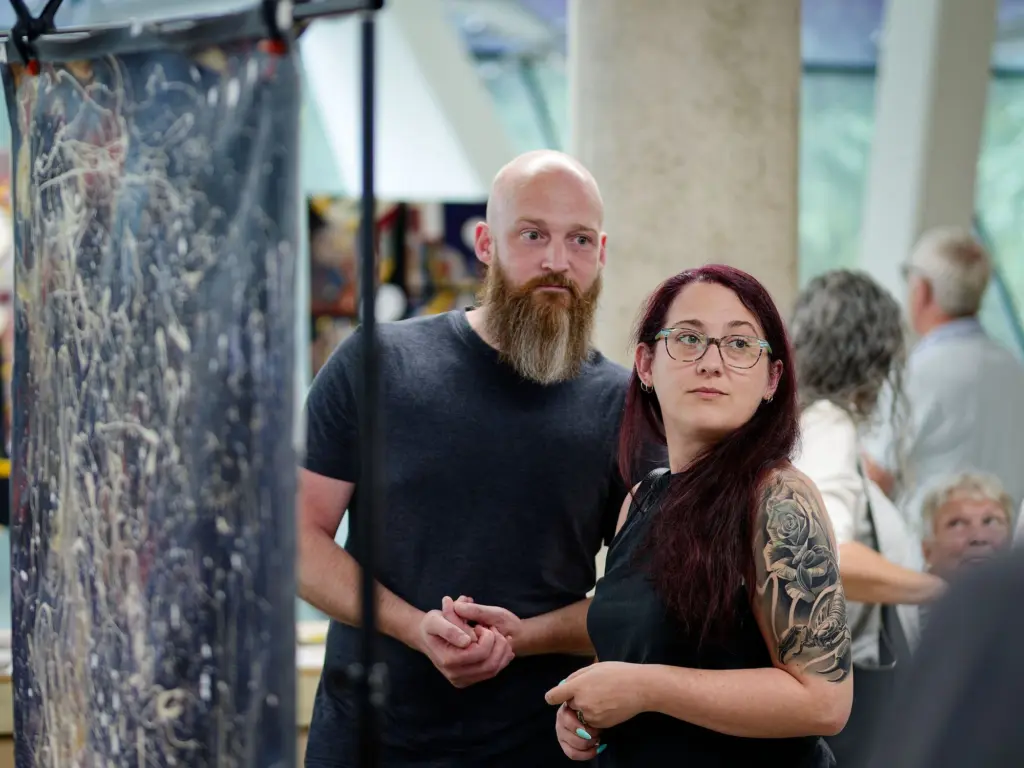 Two guests in front of a large tangled abstract canvas