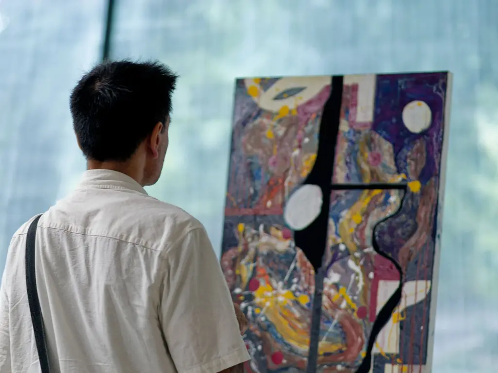 A visitor viewing three tall abstract panels