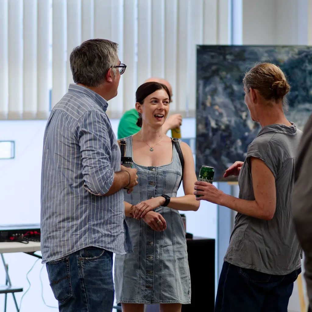 Guests in conversation beneath the hung artwork